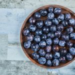 Garden plums in a plate on a blue background